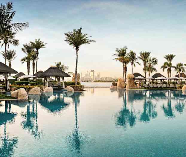 Utsikt over et basseng foran resorten med palmer og parasoller. (AI-generert tekst)