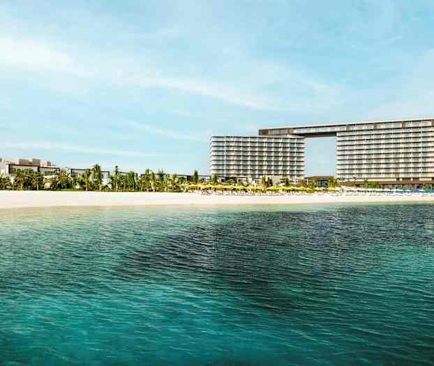 Utsikt over et hotell nær en sandstrand med klart vann. (AI-generert tekst)