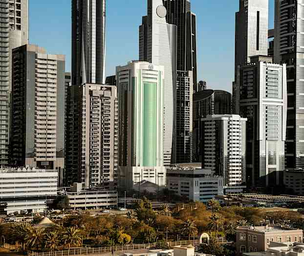 Høye, moderne bygninger omgitt av grøntområder og parker. (AI-generert tekst)