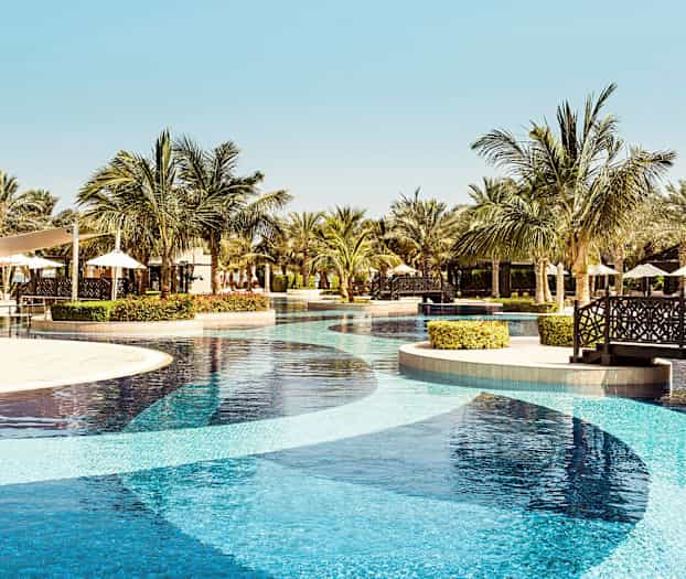 Et resortbasseng med palmer og sitteplasser i bakgrunnen. (AI-generert tekst)