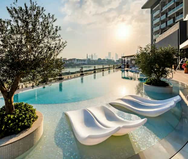 Bilde av et infinitybasseng ved solnedgang med moderne solsenger og omkringliggende vegetasjon. (AI-generert tekst)