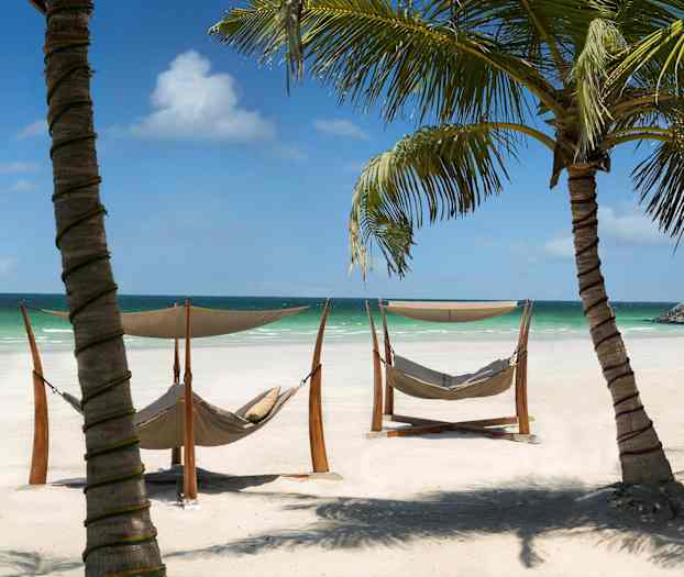 Solrike strender med hengekøyer og palmer ved havet. (AI-generert tekst)