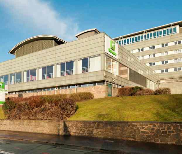 Holiday Inn-hotell i en moderne bygning med omkringliggende plen og busker. (AI-generert tekst)