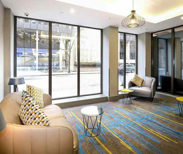 Rom med store glassvinduer, lenestoler og små bord. (AI-generert tekst)