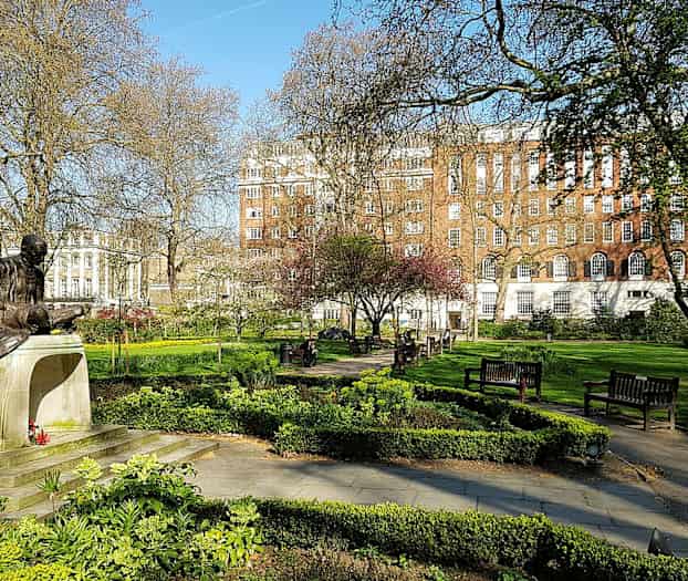 Statue i en park med grøntområder og benker. (AI-generert tekst)