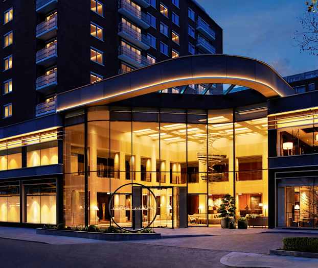 Hotellbygning med stor glassfasade og kveldsbelysning. (AI-generert tekst)