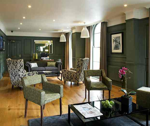 En elegant hotellounge med lenestoler og sofaer, pynteplanter og moderne interiør. (AI-generert tekst)