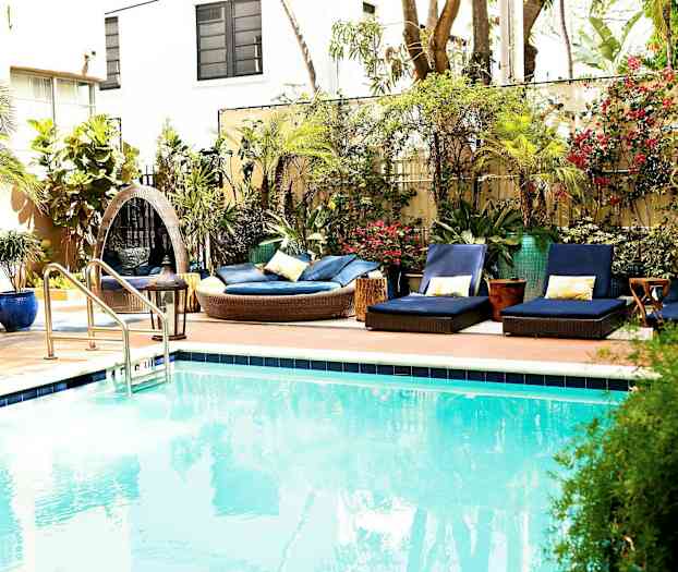 Et utendørs svømmebasseng med omkringliggende solsenger og vegetasjon. (AI-generert tekst)