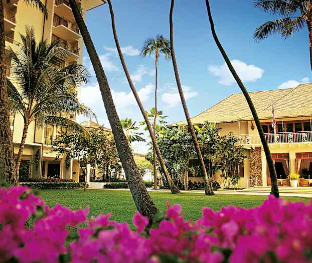 En bygning omgitt av grøntområder med palmer og blomster i forgrunnen. (AI-generert tekst)