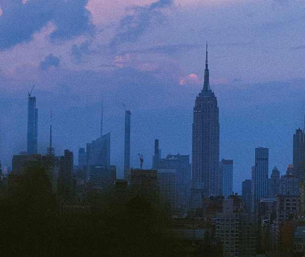 Utsikt over en byens skyline i skumringen, med flere skyskrapere mot en fargerik himmel. (AI-generert tekst)