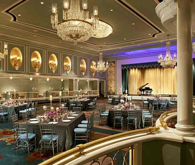 Elegant ballsal dekorert med lysekroner, dekkede bord og en scene med et flygel. (AI-generert tekst)