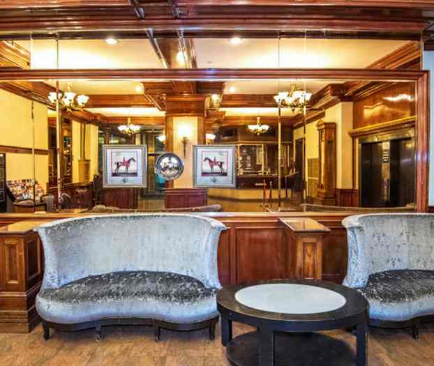 En hotellobby med to buede sofaer, et rundt bord og tremøbler i bakgrunnen. (AI-generert tekst)