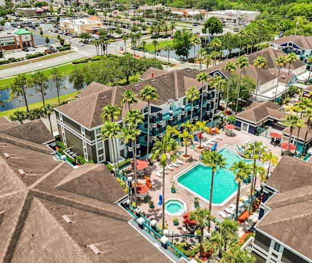 Bilde av et ferieanlegg med svømmebasseng og omkringliggende bygninger, sett ovenfra. (AI-generert tekst)