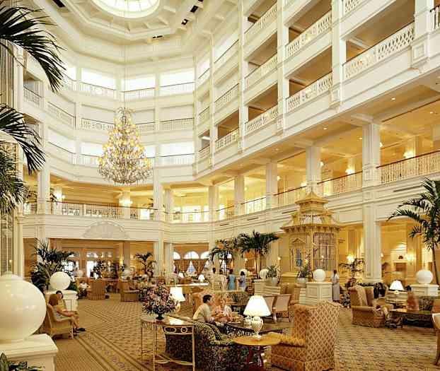 En stor og elegant hotellobby med høyt tak, en storslått lysekrone, komfortable sitteplasser og planter som dekorasjon. (AI-generert tekst)