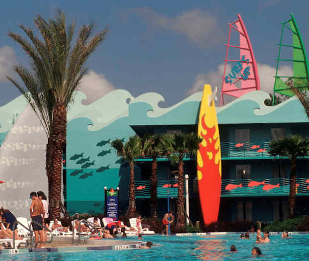 Et basseng omgitt av solsenger og mennesker. Bak står en bygning med fargerik dekorasjon av bølger, fisker og et stort surfebrett. (AI-generert tekst)