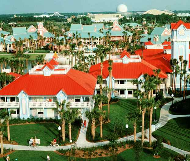 Bilde av et feriested med bygninger med rødt tak og lyseblå fasader, palmetrær og gangveier. (AI-generert tekst)