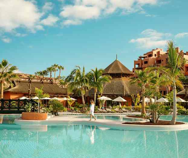 Tropisk resort med palmer, basseng og tradisjonelle bygninger. (AI-generert tekst)