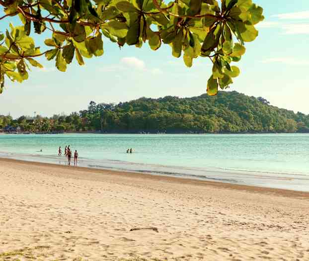 En sandstrand med mennesker, havet og en skogkledd øy i bakgrunnen. (AI-generert tekst)