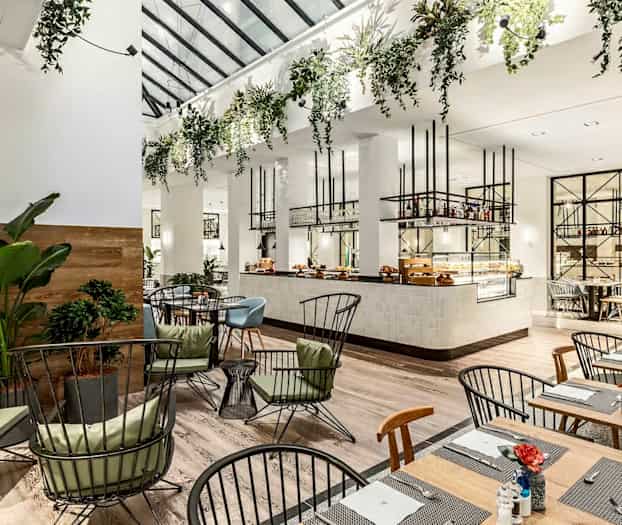 Moderne restaurant med elegante møbler og grønne planter. (AI-generert tekst)