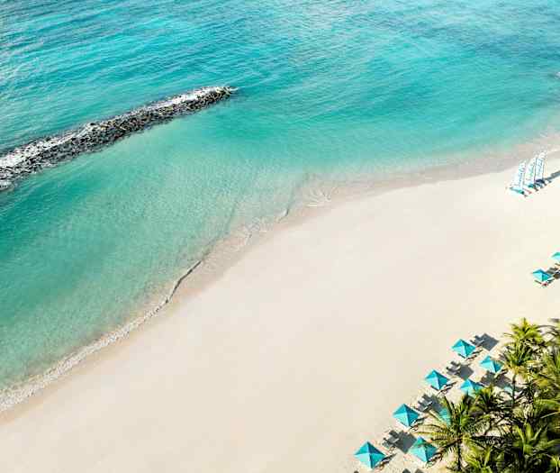 En sandstrand med turkis hav og parasoller. (AI-generert tekst)