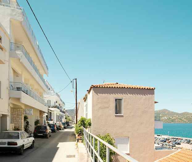 En gate med parkering og fleretasjes bygninger ved sjøen. (AI-generert tekst)