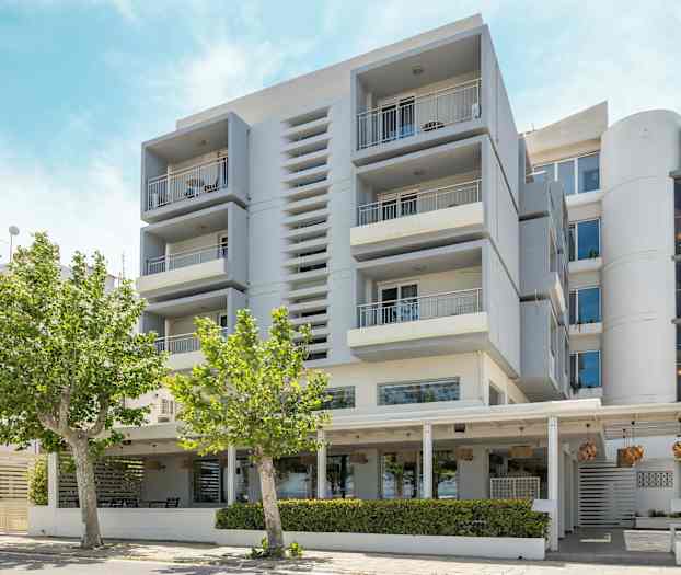 Moderne bygning med balkonger og trær i forgrunnen. (AI-generert tekst)