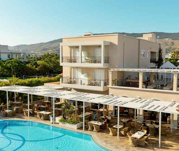 En hotellbygning med balkonger, en utendørs restaurant og et svømmebasseng i forgrunnen. (AI-generert tekst)