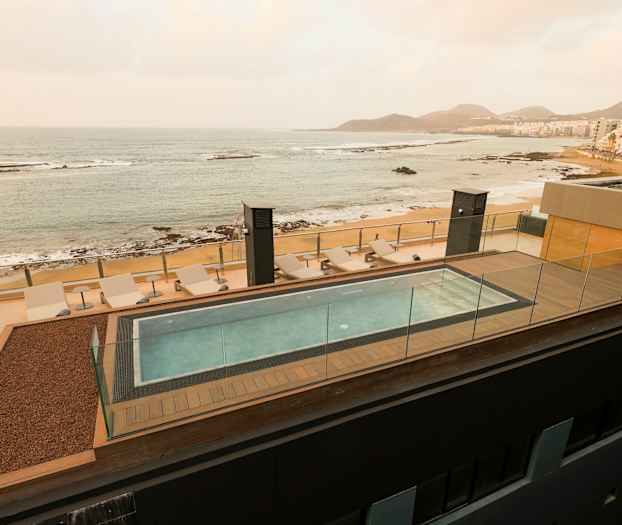 Takbasseng med solsenger og utsikt over havet og stranden. (AI-generert tekst)