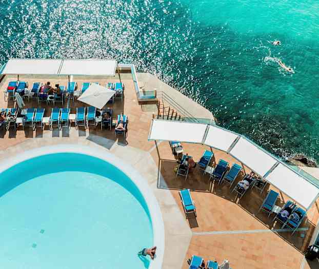 Solstoler og et basseng ved havet sett ovenfra. (AI-generert tekst)