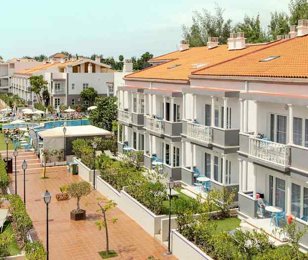 Et hotellkompleks med flere bygninger, bassengområde og hage. (AI-generert tekst)