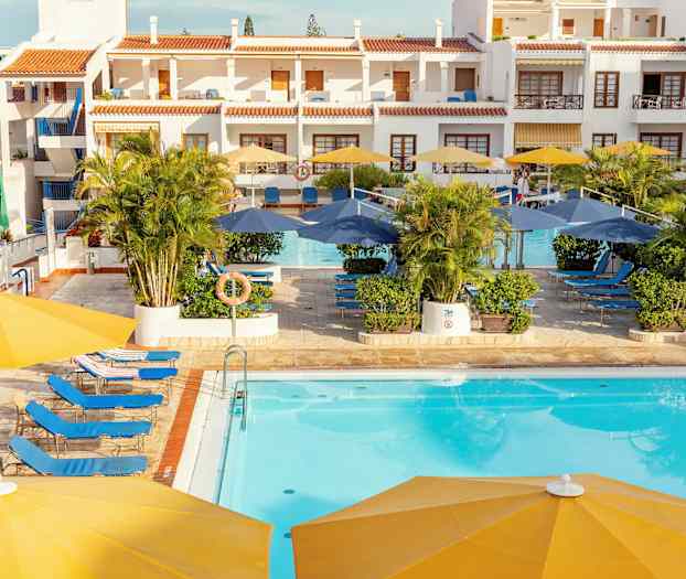 Hotellbassengets område med solsenger, parasoller og bygninger i bakgrunnen. (AI-generert tekst)