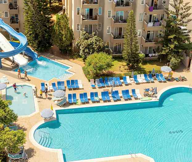 Utendørs bassengområde ved en bygning, med vannsklie og solsenger. (AI-generert tekst)