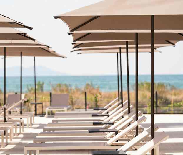 Bilde av solsenger på rekke under parasoller med utsikt mot stranden og havet. (AI-generert tekst)