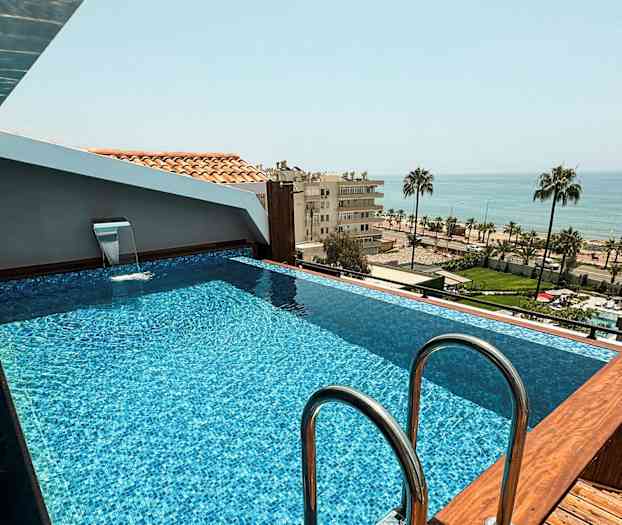 Et lite basseng på et tak med utsikt over havet og et urbant landskap. (AI-generert tekst)