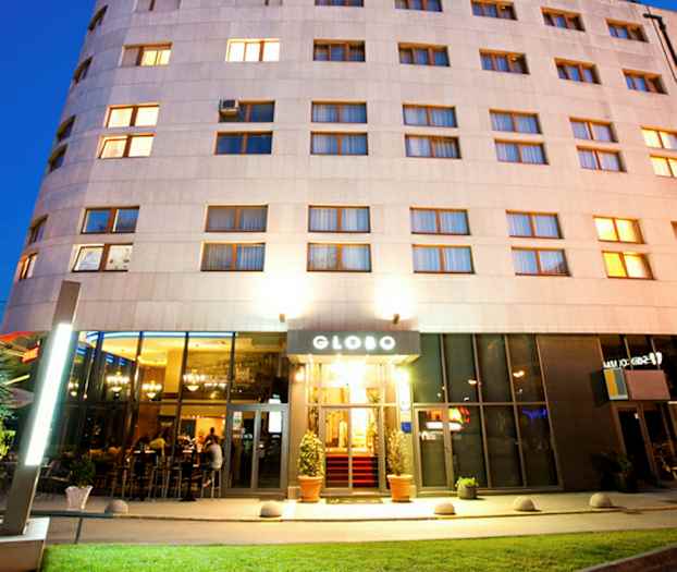 Et hotell med opplyst fasade og inngang, fotografert i skumringen. (AI-generert tekst)