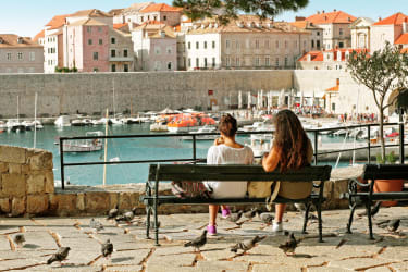 To kvinner sitter på en benk og ser mot Dubrovniks gamleby