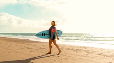 Kvinne som surfer på stranden