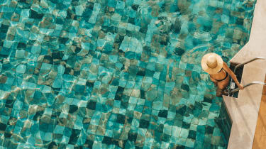 En kvinde, der går ned ad en stige i en swimmingpool iført solhat