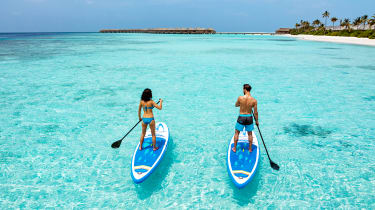 Et par står på SUP-brett på turkist hav på Maldivene