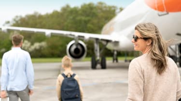 To voksne og ett barn på vei mot et fly