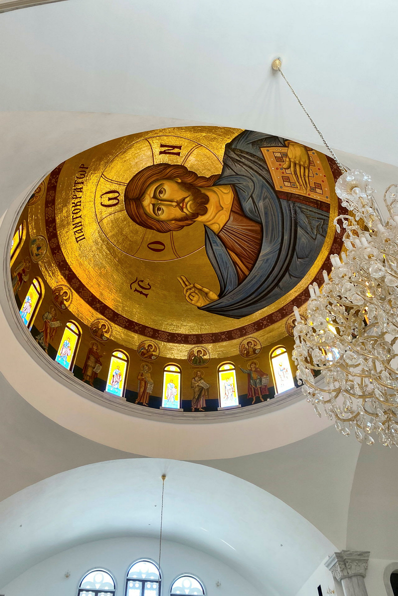 Interiør av en kirke med et dekorert tak i gyllen mosaikk og en lysekrone. (AI-generert tekst)
