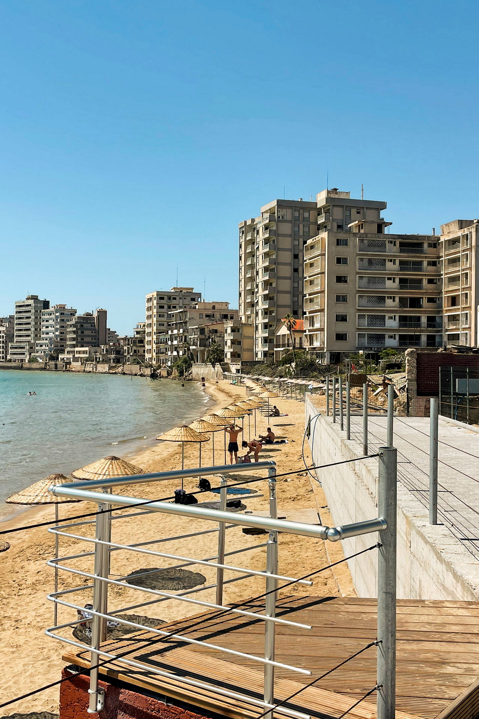 Strand med parasoller og bygninger i bakgrunnen. (AI-generert tekst)