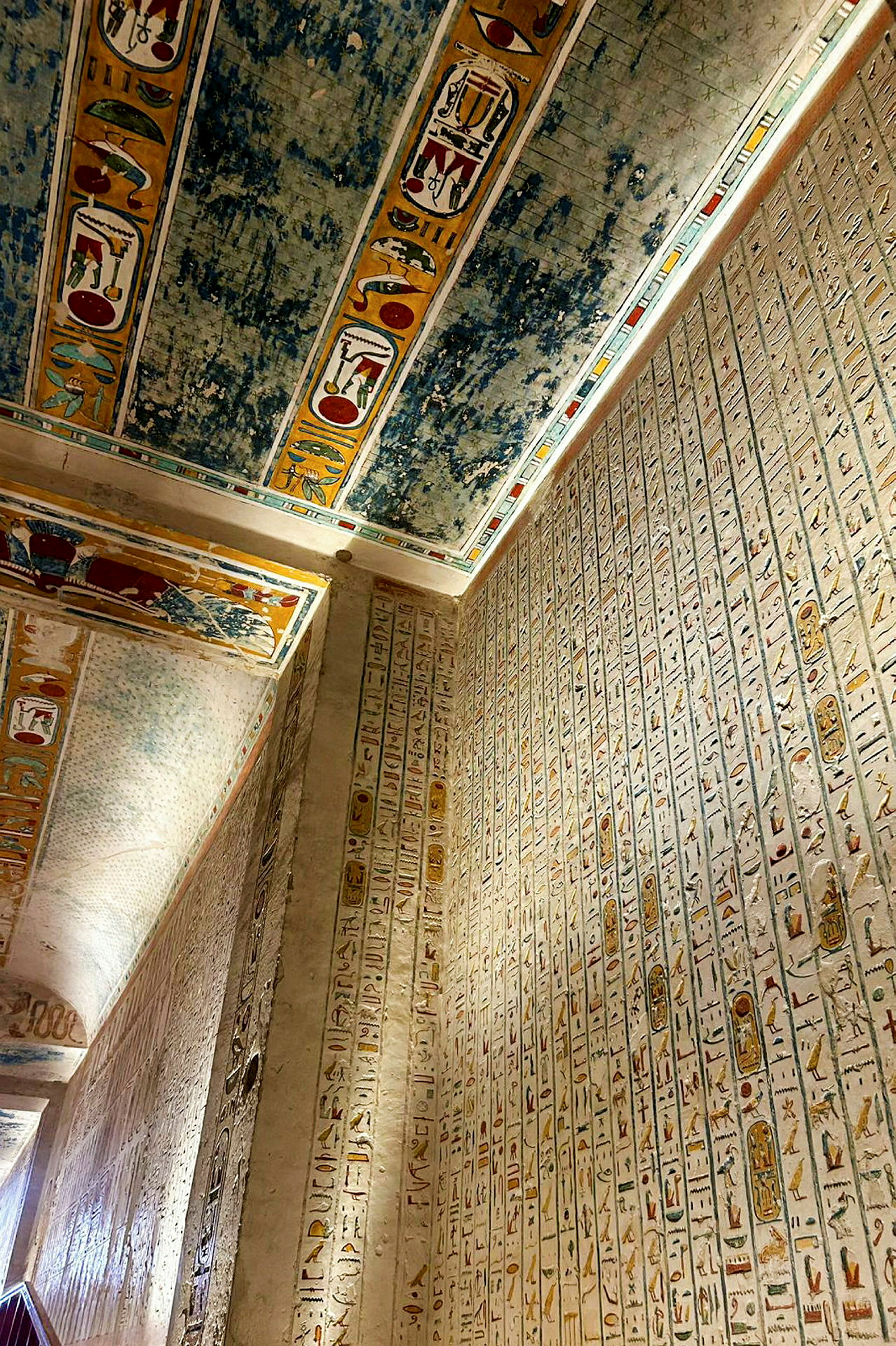 En vegg dekket med hieroglyfer og et tak med fargerike dekorasjoner i en gammel egyptisk struktur. (AI-generert tekst)