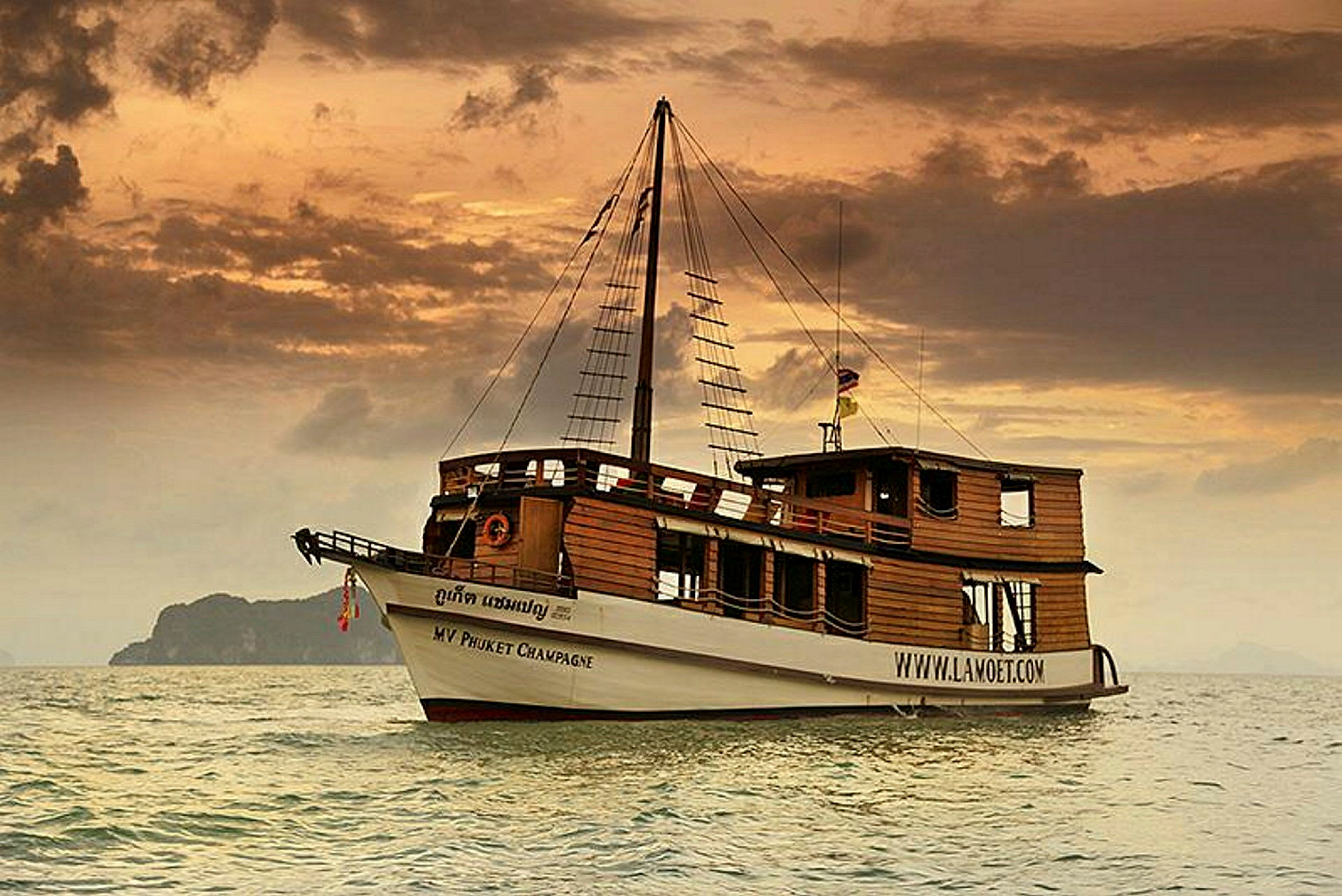 Et tradisjonelt trebåt med seilstruktur vises på havet ved solnedgang. (AI-generert tekst)