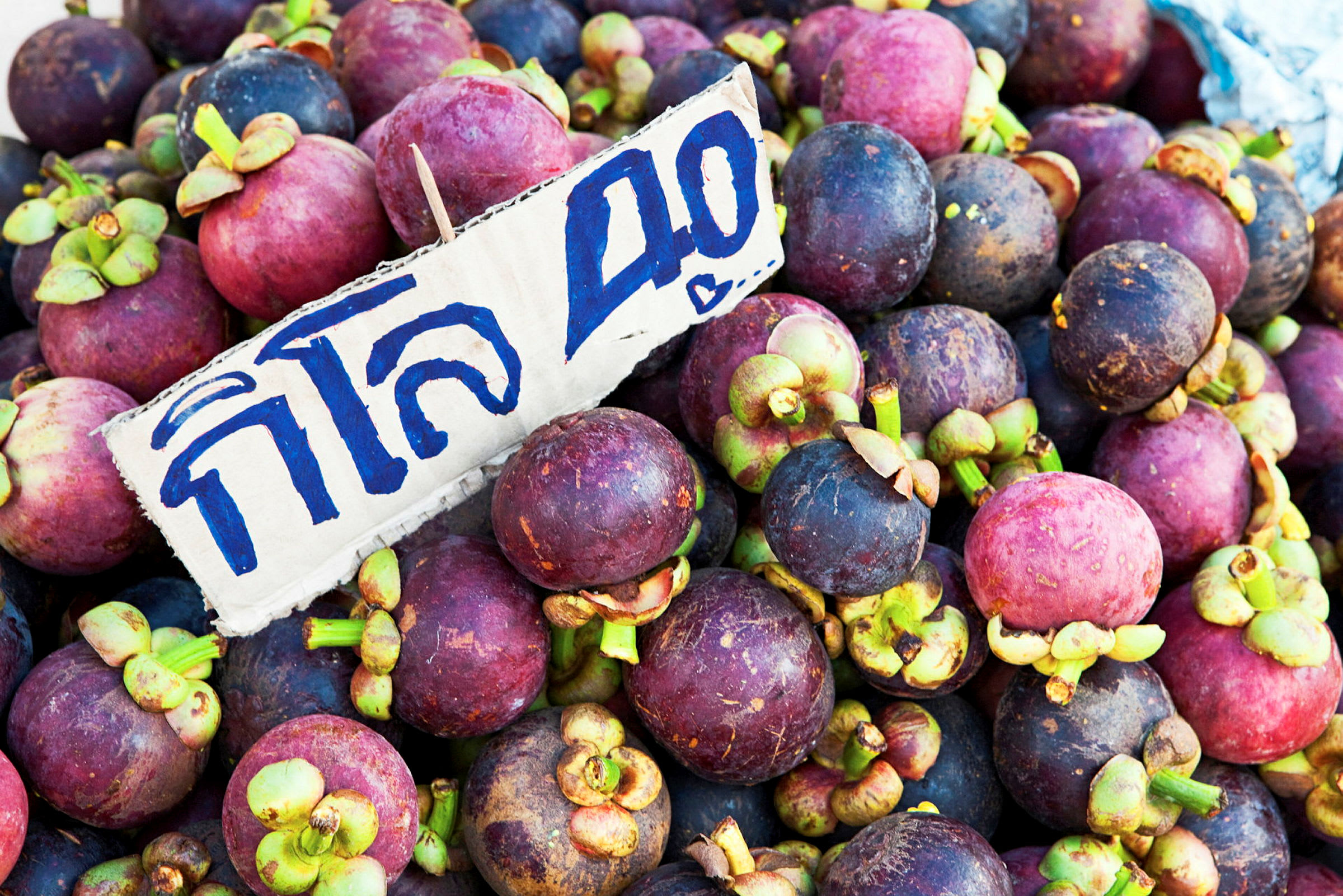 En haug med mangostanfrukt med et prisskilt. (AI-generert tekst)
