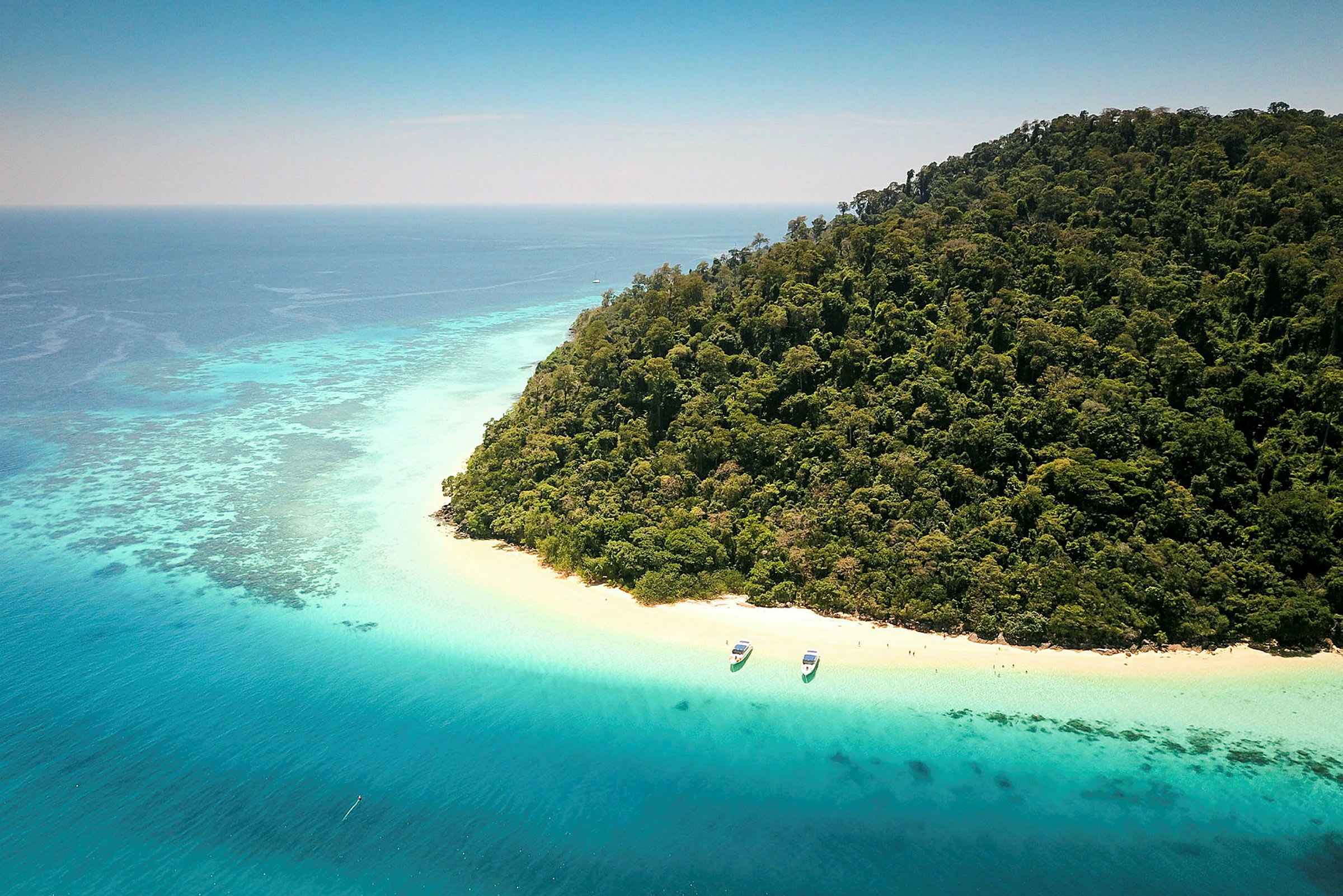 Flyfoto av en tropisk strand med turkist vann og frodig bakgrunn. (AI-generert tekst)