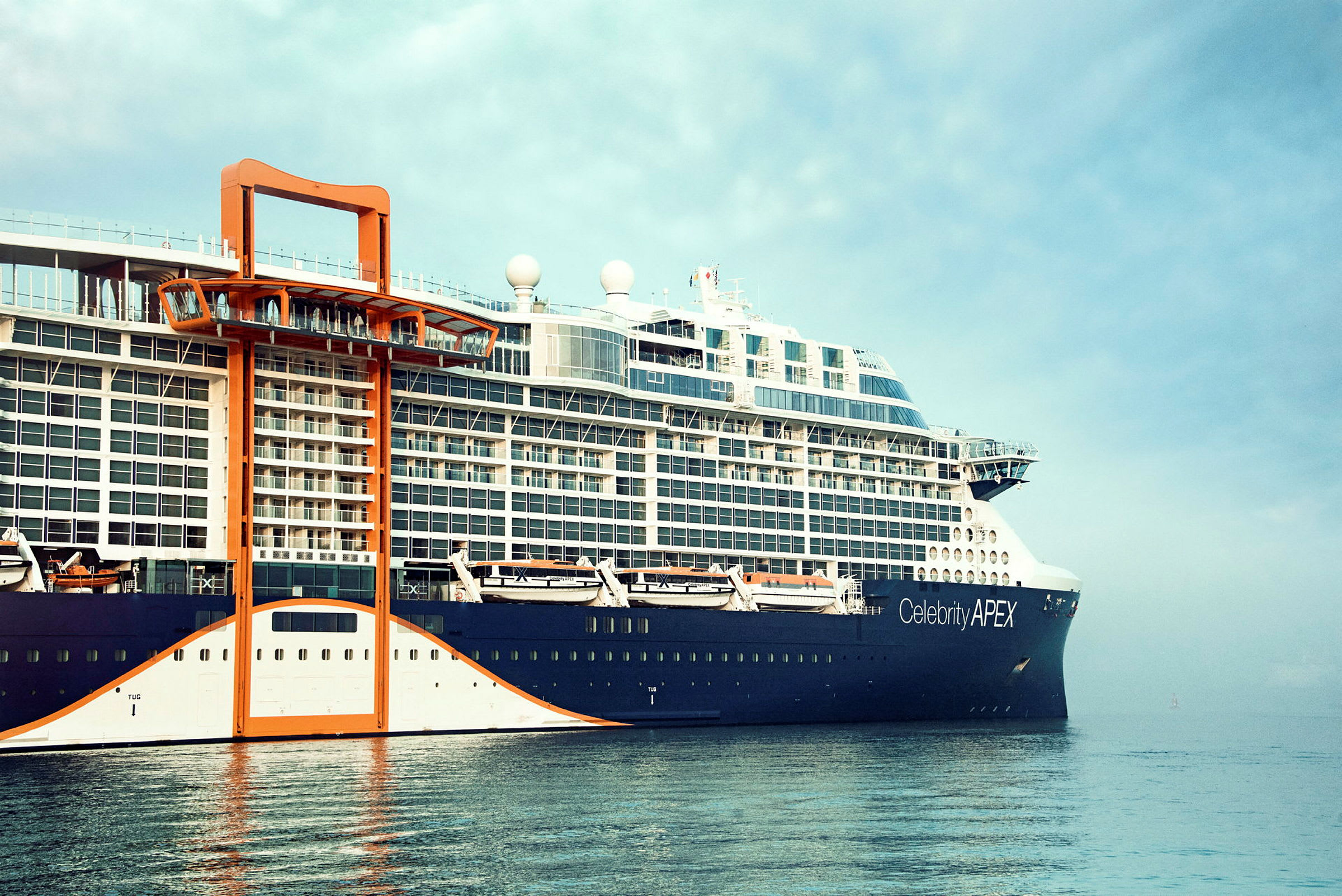 Et stort cruiseskip ligger ved kai med en klar himmel over. (AI-generert tekst)