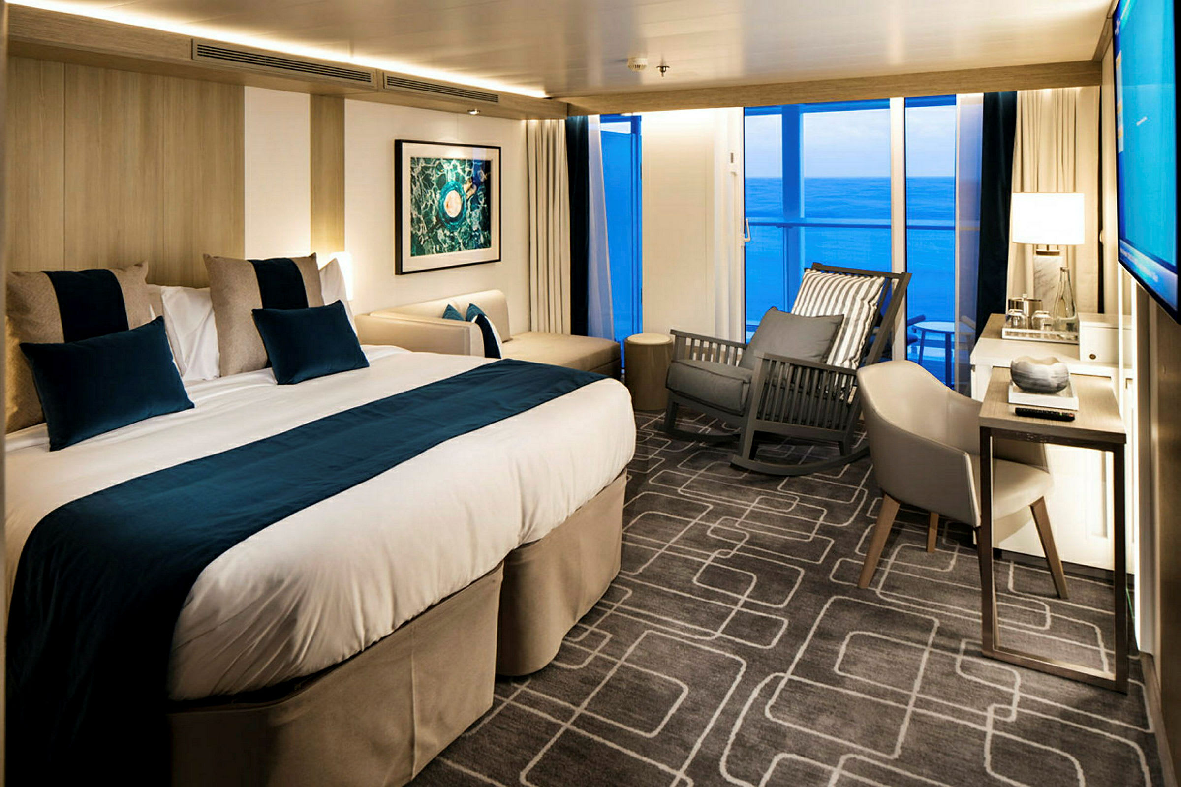 Hotellrom med dobbeltseng, stol og utsikt mot havet. (AI-generert tekst)