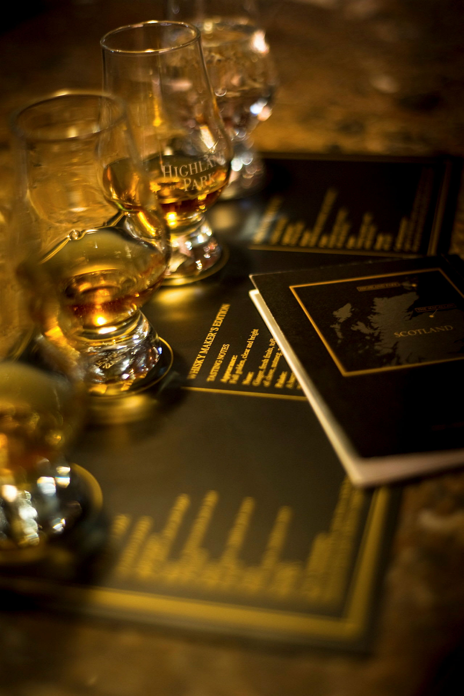 Flere glass med whisky står på et bord med brosjyrer i bakgrunnen. (AI-generert tekst)