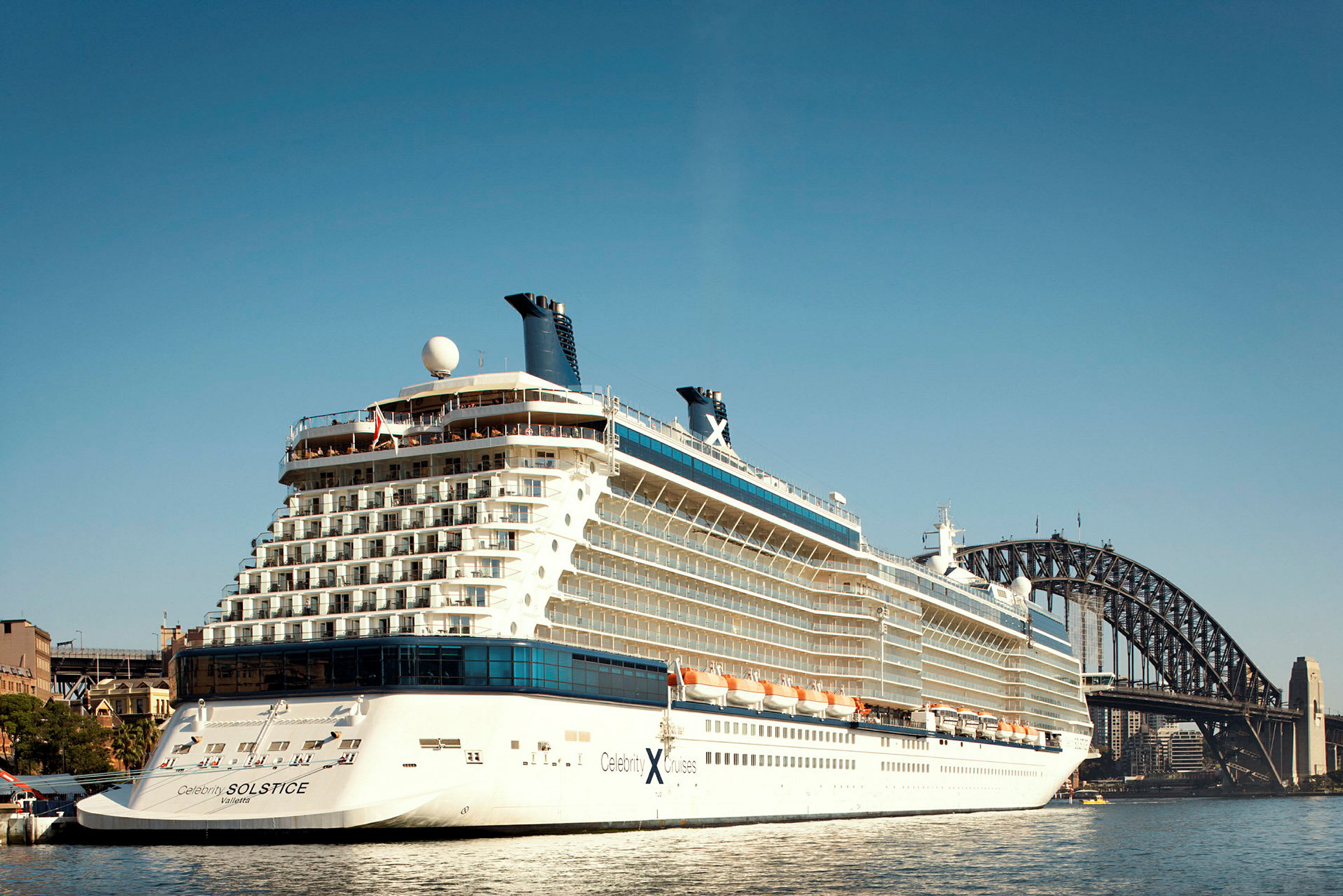 Bilde av et cruiseskip i havnen med en bro i bakgrunnen. (AI-generert tekst)
